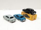 three toy cars are sitting on a white surface next to a box