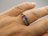 la main d'une personne tenant une bague sertie de pierres multicolores