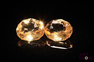 pair of yellow sapphires on a black surface with a black background