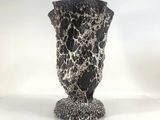 a black and white vase sitting on a white surface