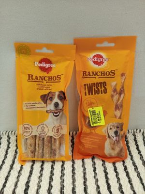 two bags of dog treats sitting on top of a bed