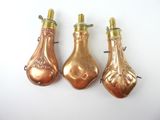 three antique copper bottle shaped ornaments on a white surface