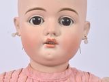 a small doll with a bald head and a pink dress