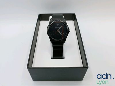 la montre se trouve dans un coffret noir posé sur une surface blanche