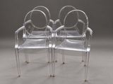 two clear plastic chairs with gold legs and arms on a gray surface