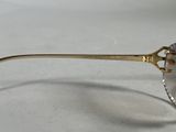 sunglasses with a gold rim and a clear lens on a white surface