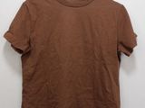 a brown t - shirt hanging on a hanger against a white wall