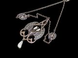 collier en argent avec un pendentif en forme de feuille et de perle sur fond noir