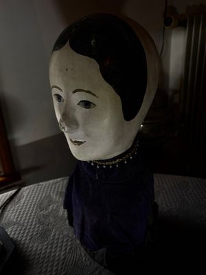 une statue représentant une femme assise sur un lit, à côté d'un ordinateur portable