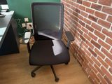 a black office chair in front of a brick wall