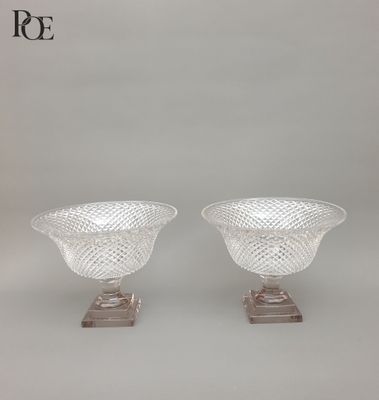 une paire de vases en verre transparent posés sur des socles, sur fond blanc