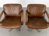 pair of brown leather swivel chairs with chrome legs