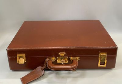 une valise marron posée sur une surface blanche