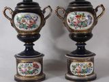 pair of black and gold vases with flowers on them on a white background