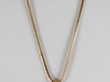 un collier en or orné d'un cachet de cire sur un mannequin blanc