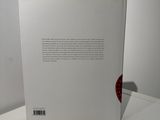 an open book sitting on top of a white table next to a red apple