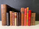Plusieurs vieux livres sont alignés sur une étagère devant un mur noir