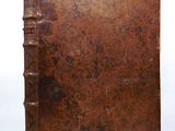 an old book with a brown cover sitting on top of a white surface