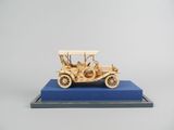 maquette en bois d'une voiture ancienne exposée sur un socle bleu