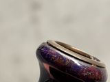 a purple vase with a gold rim sitting on a table