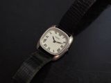 a silver watch with roman numerals on a black strap