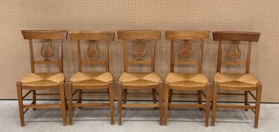 Quatre chaises en bois sont alignées en rang contre un mur