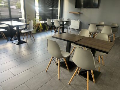 des tables et des chaises dans un restaurant où est accrochée une télévision à écran plat au mur