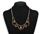a black mannequin with a gold necklace on it