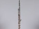 a silver flute sitting on top of a table next to a glass