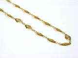 a close up of a gold necklace with a chain on a white surface
