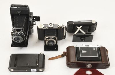 un grand nombre de vieux appareils photo posés sur une surface blanche