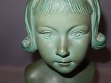 a green statue of a young girl with short hair