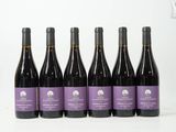 six bouteilles de vin sont alignées sur une surface blanche