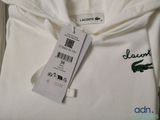 a label on a white sweatshirt with a crocodile on it
