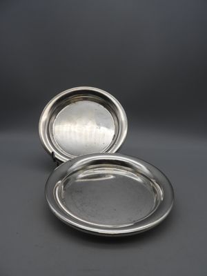 a pair of silver plated dishes on a grey background