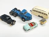 cinq petites voitures et un bus posés sur une surface blanche