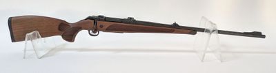 le fusil est posé sur un support transparent, sur une surface blanche