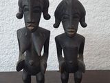 une paire de statues en bois représentant un homme et une femme assis sur une table