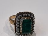 a close up of a ring with a green stone surrounded by small diamonds