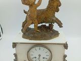 une petite horloge surmontée d'une statuette de chèvre