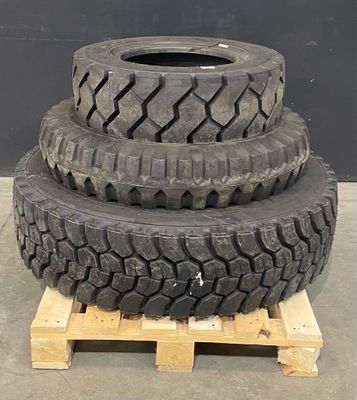 three tires stacked on pallets in front of a black wall