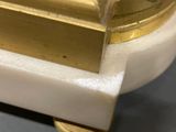 a close up of a gold and white clock on a table
