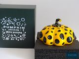 a yellow and black pumpkin sitting on top of a black box