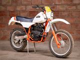 a white and orange dirt bike parked in front of a brick wall