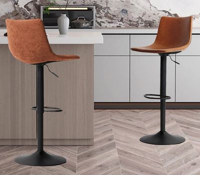 Deux tabourets de bar en cuir marron sont disposés devant le comptoir de la cuisine.