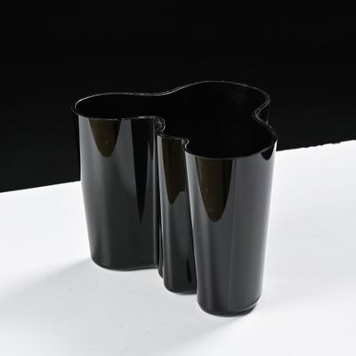 two black vases on a white table with a black background
