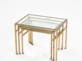 a set of three brass nesting tables with a glass top