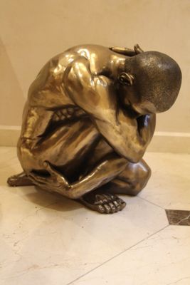 une statue en bronze représentant un homme assis par terre