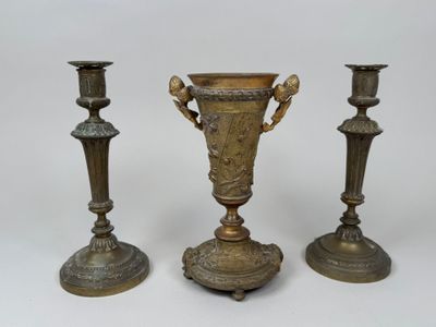 trois vases en laiton vieilli posés les uns à côté des autres sur une surface blanche