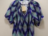 a blue and green blouse hanging on a hanger